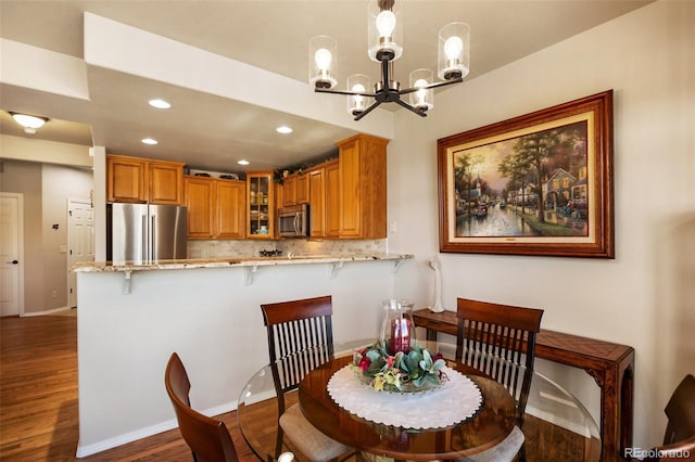 dining room with dark wood-type flooring, a notable chandelier, recessed lighting, and baseboards