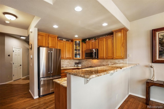 kitchen featuring stainless steel appliances, brown cabinets, backsplash, and a peninsula