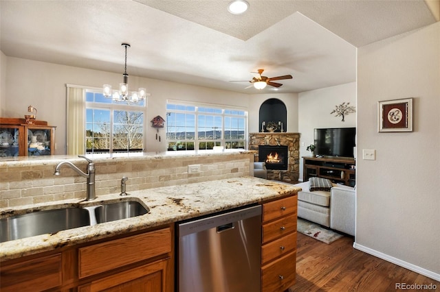 kitchen featuring dark wood-type flooring, ceiling fan with notable chandelier, a sink, stainless steel dishwasher, and brown cabinetry