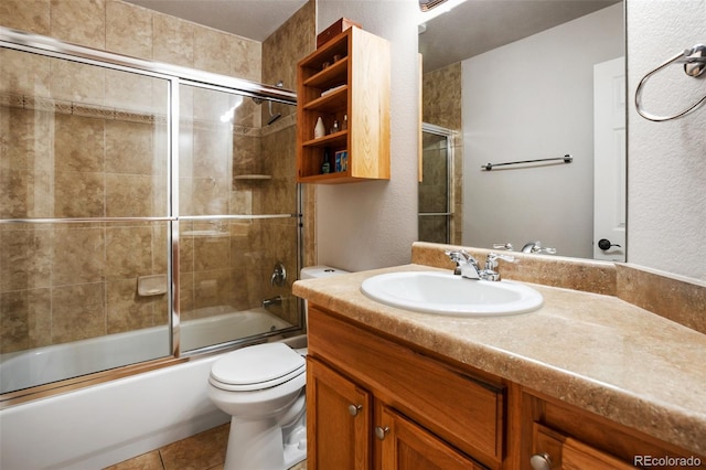 full bath with tile patterned floors, toilet, a textured wall, enclosed tub / shower combo, and vanity