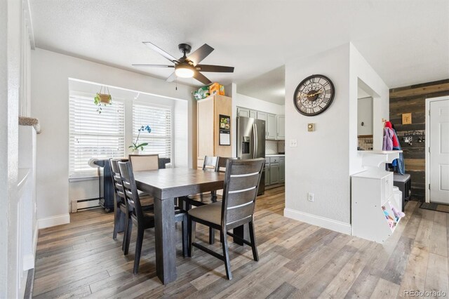 3660 S Ouray Cir, Aurora, CO 80013 - dining space featuring ceiling fan, baseboard heating, light wood-style floors, and wooden walls