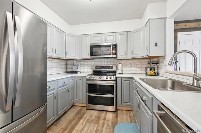 3660 S Ouray Cir, Aurora, CO 80013 - kitchen with appliances with stainless steel finishes, gray cabinets, light wood-style floors, backsplash, and light countertops