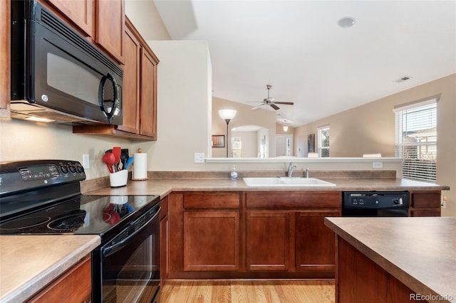 kitchen featuring light hardwood / wood-style floors, ceiling fan, lofted ceiling, black appliances, and sink