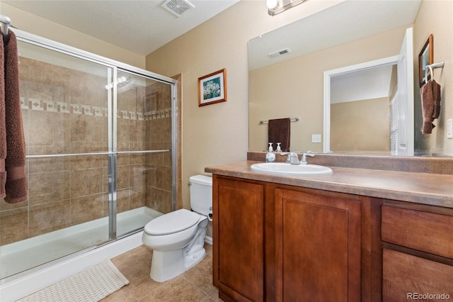 bathroom featuring toilet, vanity, tile patterned flooring, and a shower with door