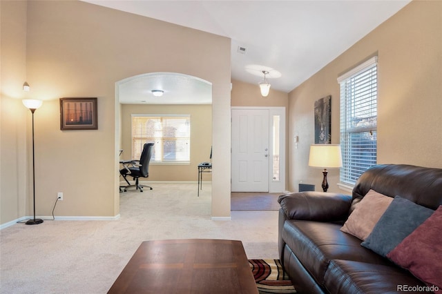 living area featuring light carpet, arched walkways, baseboards, lofted ceiling, and visible vents