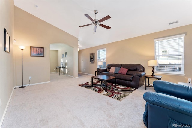 living room featuring a ceiling fan, light colored carpet, visible vents, arched walkways, and high vaulted ceiling