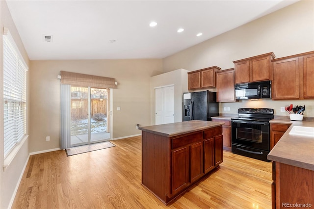 kitchen with brown cabinetry, light wood-style flooring, a center island, lofted ceiling, and black appliances