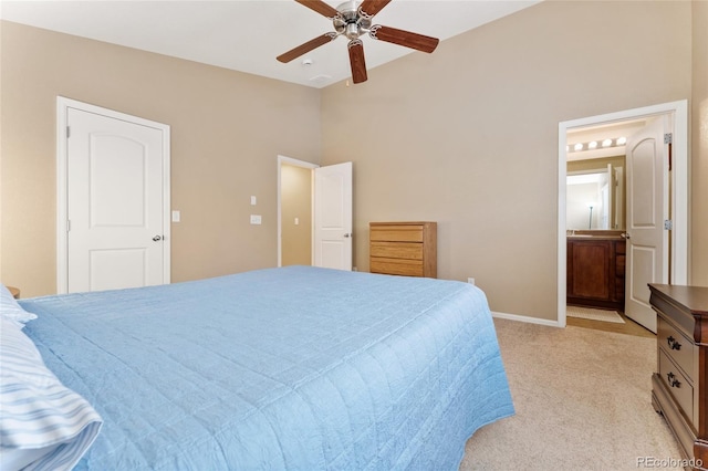 bedroom featuring lofted ceiling, baseboards, ensuite bathroom, light colored carpet, and a ceiling fan