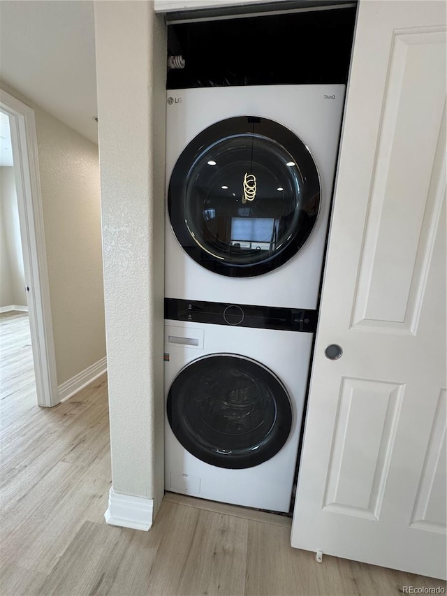 laundry room featuring light hardwood / wood-style floors and stacked washer / drying machine