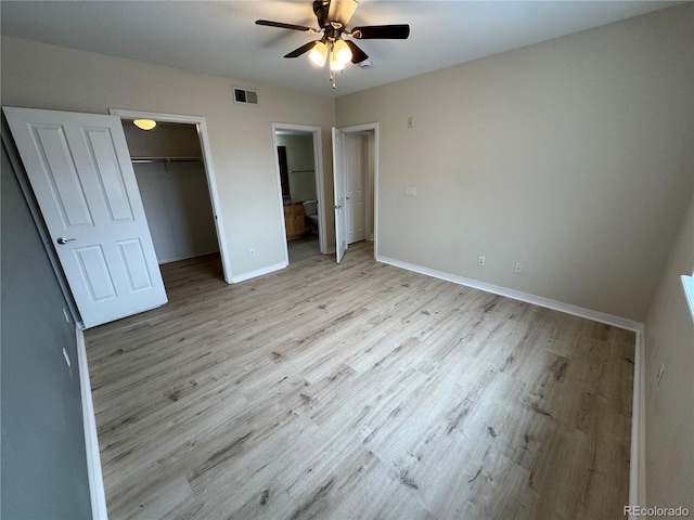 unfurnished bedroom with a walk in closet, connected bathroom, light hardwood / wood-style floors, a closet, and ceiling fan