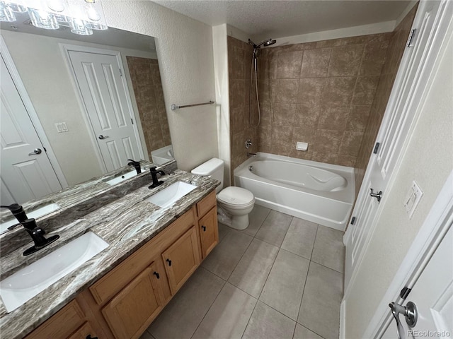 full bathroom featuring tile patterned flooring, tiled shower / bath, a textured ceiling, toilet, and vanity