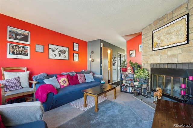 living room with carpet floors, an accent wall, a textured ceiling, and a stone fireplace