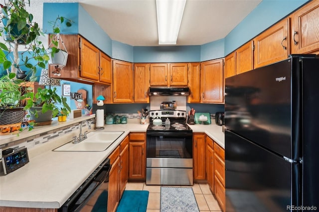 kitchen featuring black appliances, a sink, under cabinet range hood, brown cabinetry, and light countertops