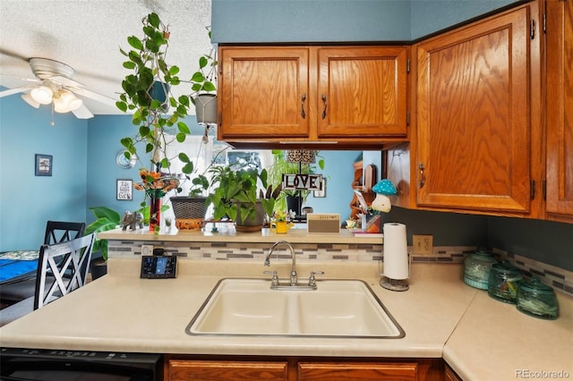 kitchen with a sink, light countertops, ceiling fan, brown cabinets, and tasteful backsplash