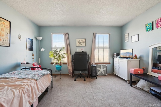 carpeted bedroom featuring multiple windows, a textured ceiling, and an office area