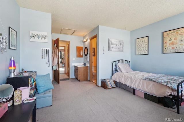 bedroom featuring attic access, light carpet, and a textured ceiling