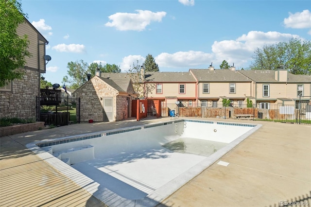 view of swimming pool with a residential view, fence, a patio area, and an outbuilding