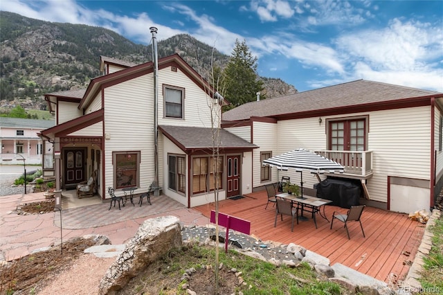 200 Rose St, Georgetown, CO 80444 - rear view of house featuring a deck with mountain view, outdoor dining area, roof with shingles, and a patio area