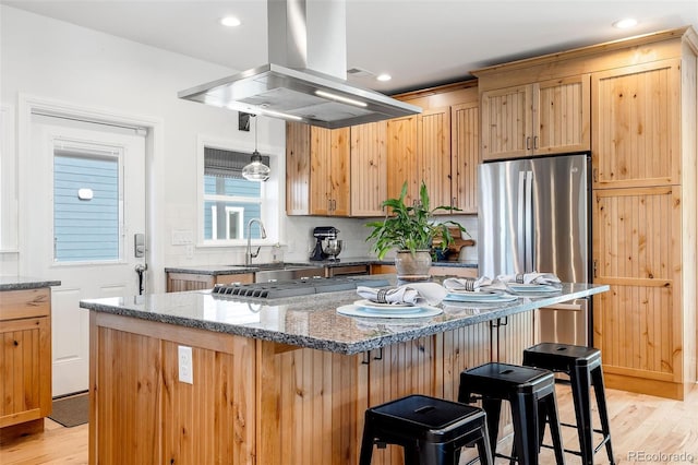 2221 Illinois St, Golden, CO 80401 - kitchen featuring island range hood, stainless steel appliances, light wood finished floors, a breakfast bar, and stone counters