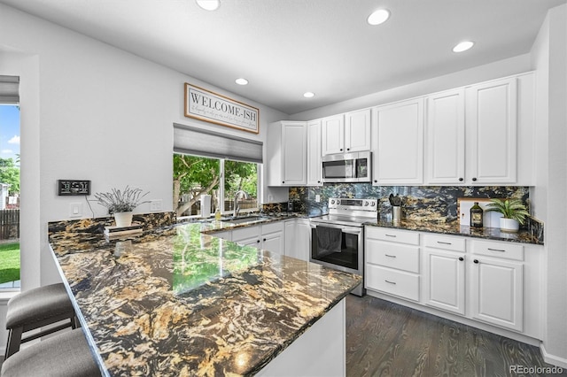 17395 E Dewberry Dr, Parker, CO 80134 - kitchen featuring appliances with stainless steel finishes, a sink, a peninsula, white cabinetry, and dark stone counters