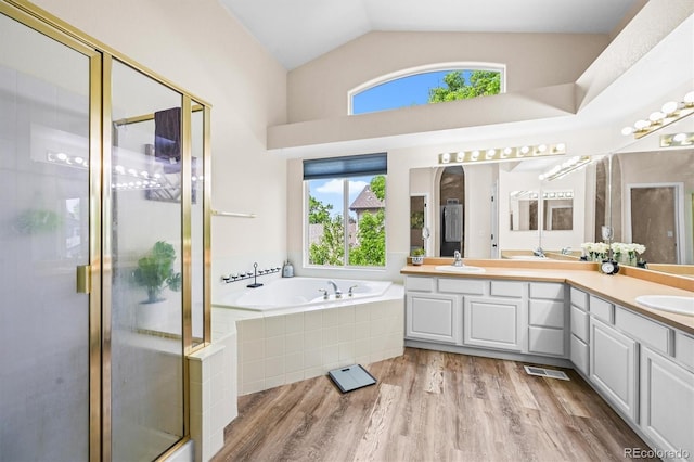 17395 E Dewberry Dr, Parker, CO 80134 - full bathroom with double vanity, a bath, a shower stall, wood finished floors, and vaulted ceiling