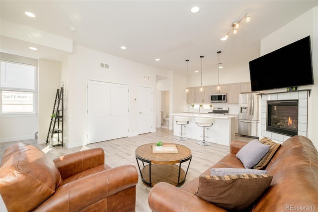 living room featuring a tile fireplace and light hardwood / wood-style floors