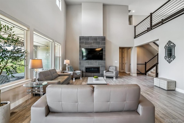 8299 S Kellerman, Aurora, CO 80016 - living room featuring a high ceiling, baseboards, wood finished floors, stairs, and a tiled fireplace