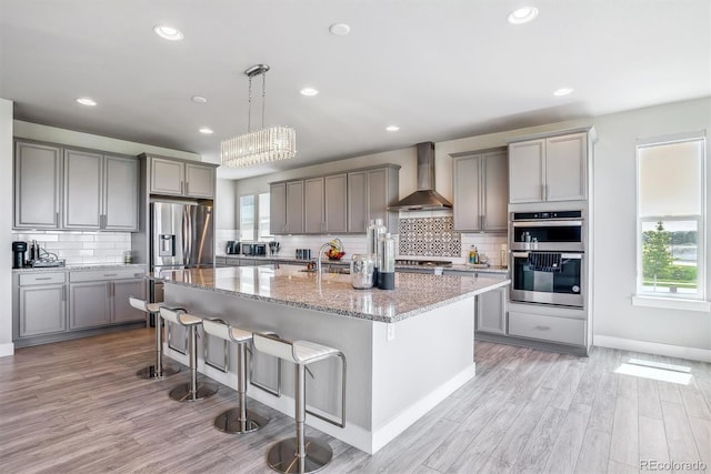 8299 S Kellerman, Aurora, CO 80016 - kitchen featuring wall chimney range hood, gray cabinets, stainless steel appliances, healthy amount of natural light, and recessed lighting