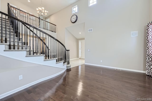 entryway with an inviting chandelier, wood-type flooring, and a high ceiling