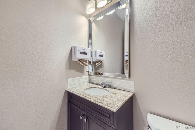 bathroom with vanity, toilet, and decorative backsplash