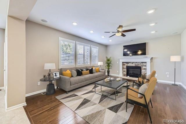 living room featuring a fireplace, wood-type flooring, and ceiling fan