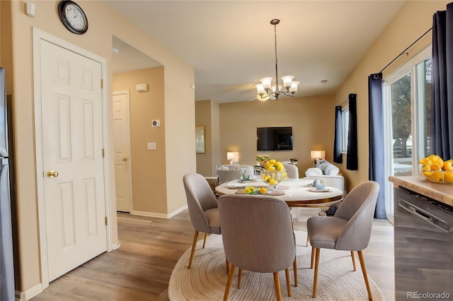 dining space featuring light hardwood / wood-style floors and a notable chandelier