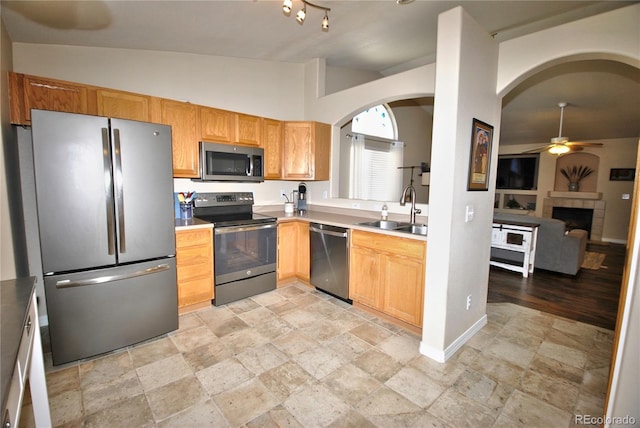 kitchen with lofted ceiling, sink, ceiling fan, a fireplace, and appliances with stainless steel finishes