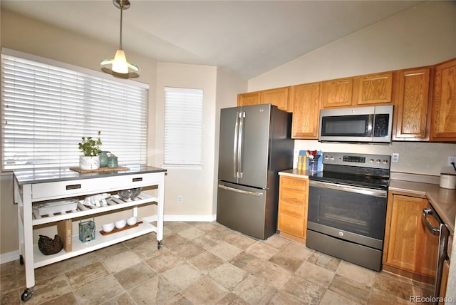 kitchen with appliances with stainless steel finishes, vaulted ceiling, and hanging light fixtures