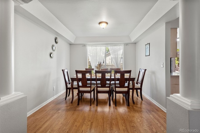 2211 S Moline Ct, Aurora, CO 80014 - dining room with light wood-style flooring, ornate columns, and a tray ceiling