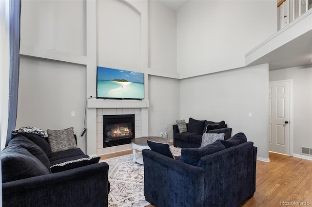 2211 S Moline Ct, Aurora, CO 80014 - living area with light wood-type flooring, a tiled fireplace, and a high ceiling