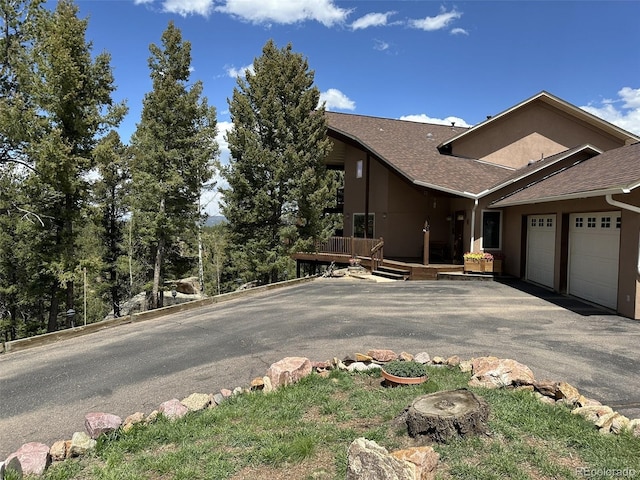319 Summit Rd, Woodland Park, CO 80863 - view of front facade featuring an attached garage, a shingled roof, asphalt driveway, and stucco siding