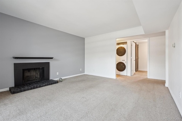 3141 S Tamarac Dr Unit 206E, Denver, CO 80231 - unfurnished living room featuring stacked washing machine and dryer, carpet, and a fireplace with raised hearth