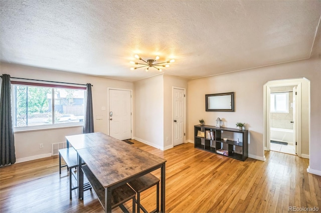 3241 Sheridan Blvd, Wheat Ridge, CO 80212 - dining space with a textured ceiling, light wood-style floors, baseboards, and arched walkways