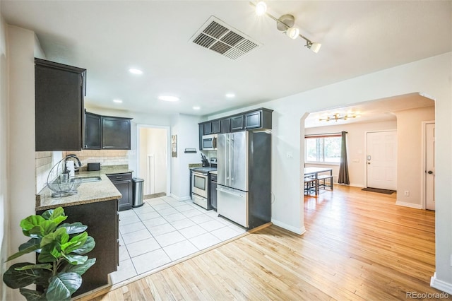 3241 Sheridan Blvd, Wheat Ridge, CO 80212 - kitchen with appliances with stainless steel finishes, a sink, arched walkways, light stone countertops, and backsplash