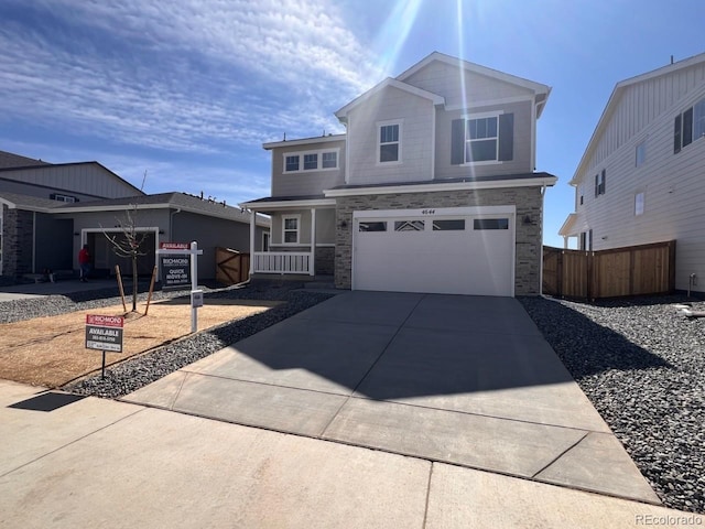 traditional-style house with stone siding, an attached garage, driveway, and fence