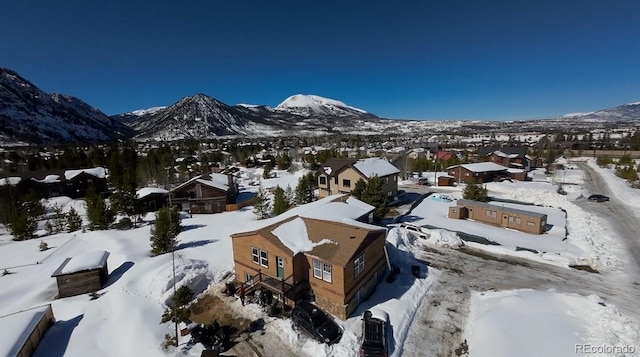 snowy aerial view with a mountain view and a residential view