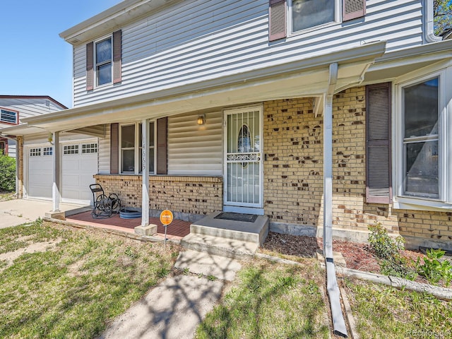 doorway to property with covered porch, brick siding, and a garage