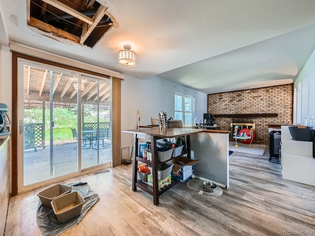 kitchen featuring wood finished floors, a wood stove, and brick wall
