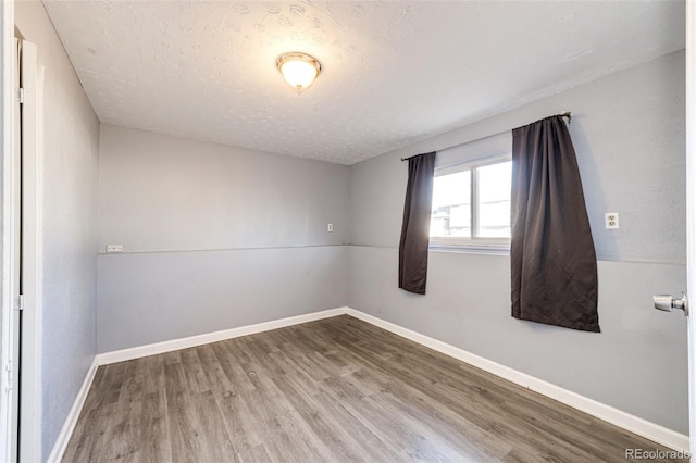 unfurnished room with a textured ceiling and hardwood / wood-style flooring