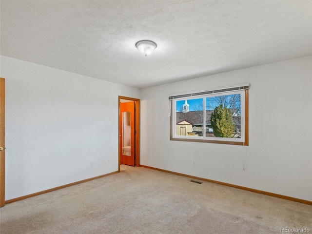 empty room featuring a textured ceiling and light colored carpet