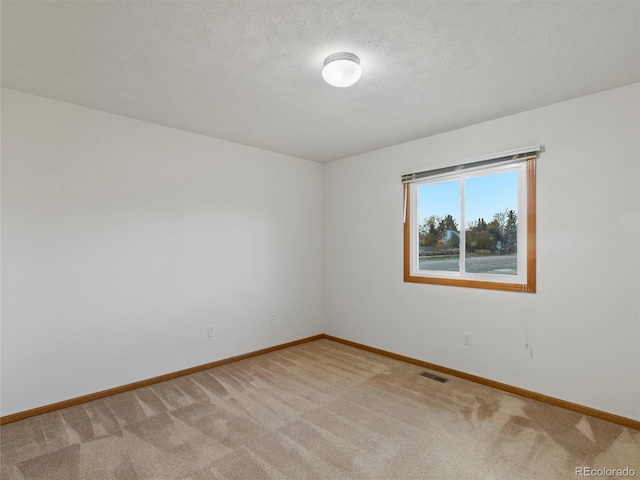 empty room featuring a textured ceiling and light colored carpet