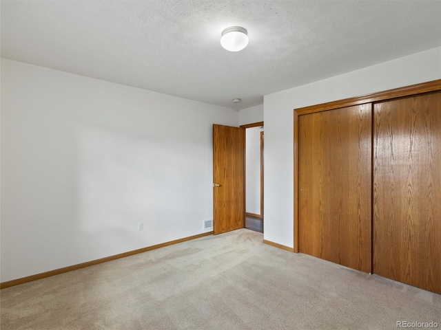 unfurnished bedroom with a closet, light colored carpet, and a textured ceiling