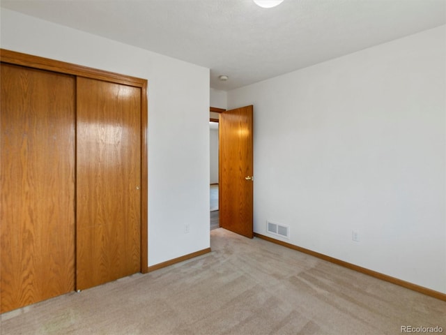 unfurnished bedroom with light colored carpet and a closet