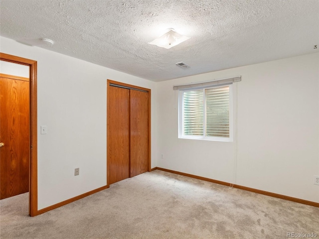 unfurnished bedroom with light carpet, a closet, and a textured ceiling